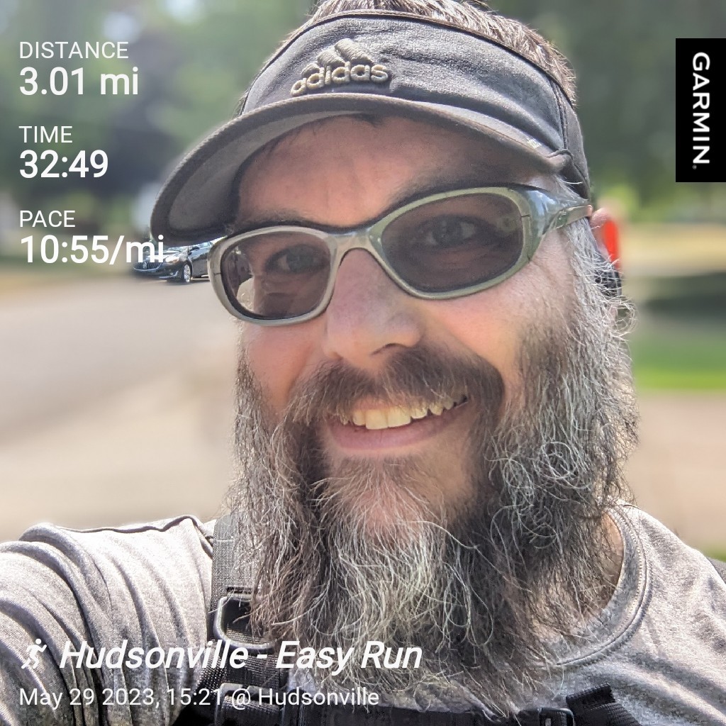Distance: 3.01 mi / Time: 32:49 / Pace: 10:55 min/mi / Hudsonville - Easy Run / Selfie of me smiling even though I'm super hot and tired, bright sunny neighborhood background.